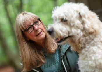 A woman with long hair carefully observes a dog as if she is hoping to learn all she can about the dog's prey drive.